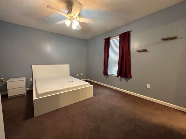 unfurnished bedroom featuring a textured ceiling, dark carpet, and ceiling fan