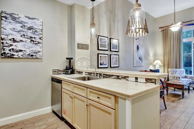 kitchen featuring ceiling fan, dishwasher, sink, decorative light fixtures, and light wood-type flooring