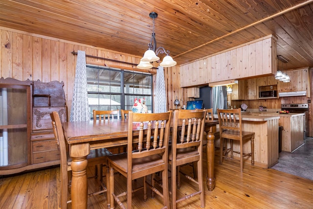 dining area featuring light hardwood / wood-style flooring, wooden walls, a chandelier, and wooden ceiling