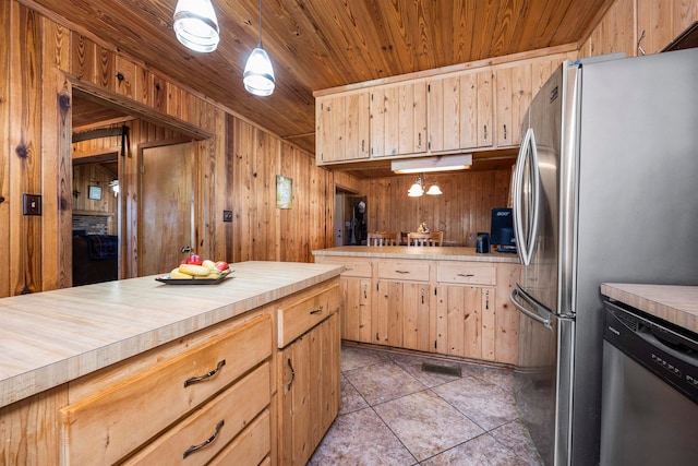 kitchen with light brown cabinets, pendant lighting, appliances with stainless steel finishes, and wooden walls