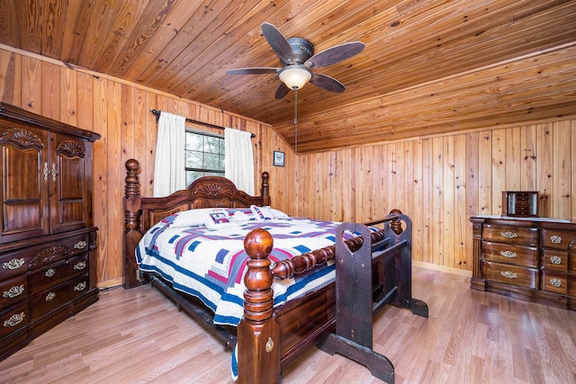 bedroom with wooden walls, light wood-type flooring, and vaulted ceiling