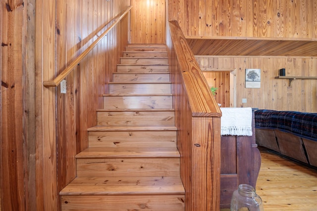 stairs featuring hardwood / wood-style flooring and wooden walls