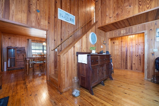 stairway with wood walls, a high ceiling, and wood-type flooring