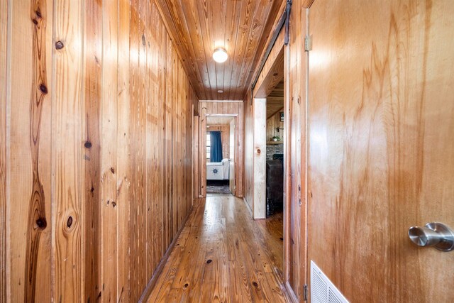 corridor with wooden walls, wood-type flooring, and wooden ceiling