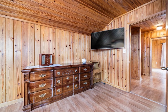 interior space featuring light wood-type flooring, wood walls, vaulted ceiling, and wood ceiling