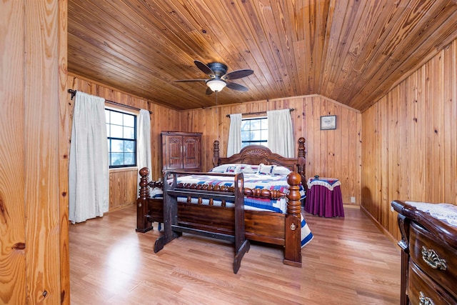 bedroom with ceiling fan, multiple windows, wooden walls, and light wood-type flooring