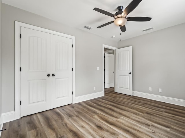 unfurnished bedroom with dark hardwood / wood-style flooring, a closet, and ceiling fan