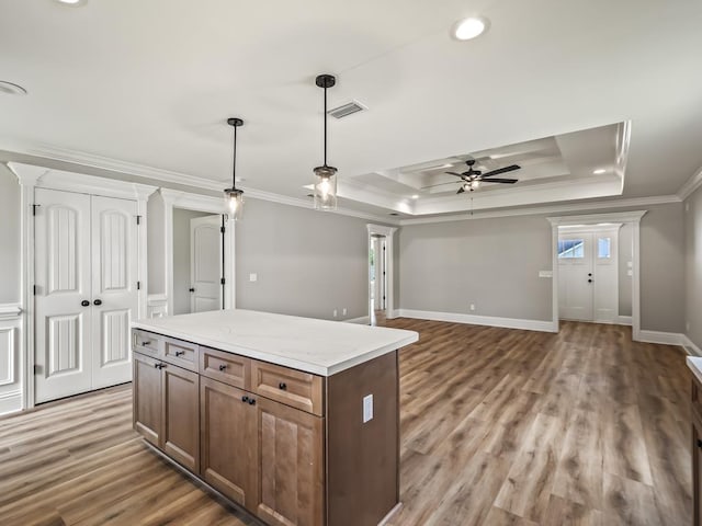 kitchen featuring a kitchen island, pendant lighting, hardwood / wood-style flooring, ornamental molding, and a tray ceiling