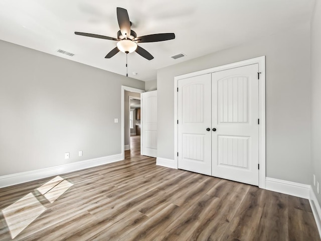 unfurnished bedroom featuring hardwood / wood-style floors, a closet, and ceiling fan