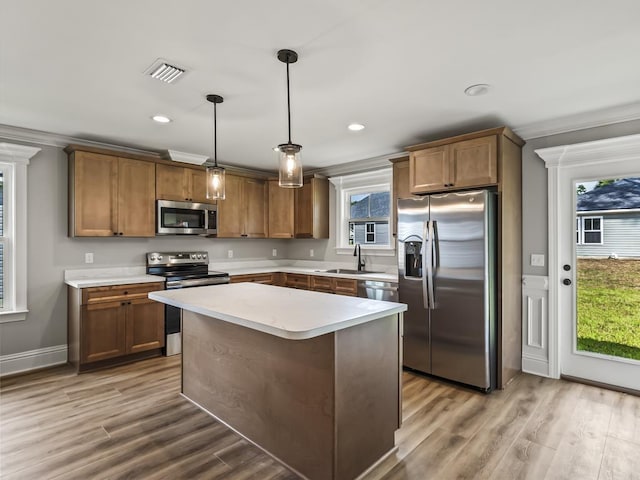 kitchen featuring sink, a center island, appliances with stainless steel finishes, pendant lighting, and hardwood / wood-style floors