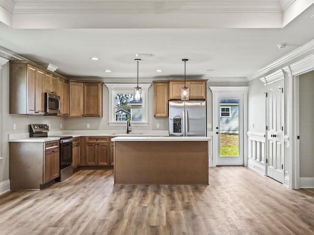 kitchen featuring sink, stainless steel appliances, ornamental molding, decorative light fixtures, and light wood-type flooring