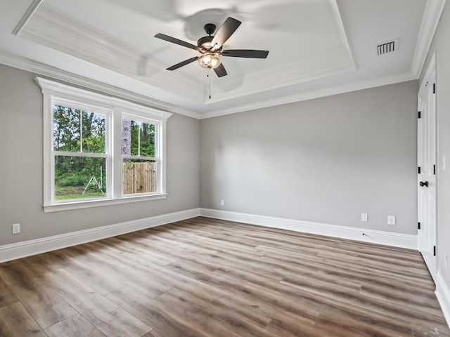 spare room with crown molding, ceiling fan, a tray ceiling, and hardwood / wood-style flooring