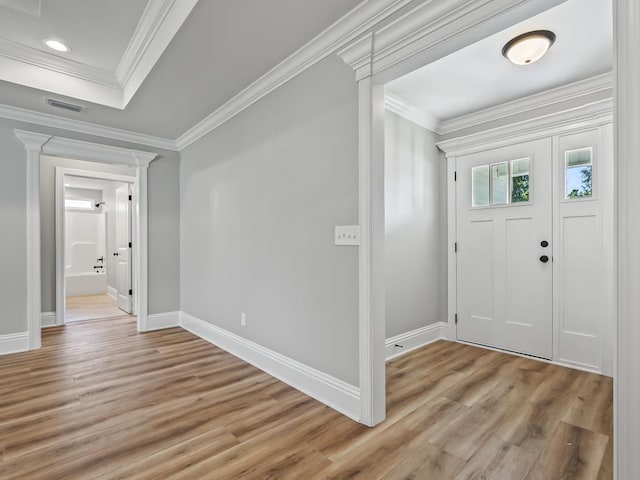 entrance foyer with decorative columns, crown molding, light hardwood / wood-style floors, and a tray ceiling