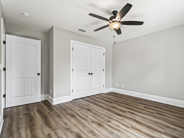 unfurnished bedroom featuring dark hardwood / wood-style floors, ceiling fan, and a closet