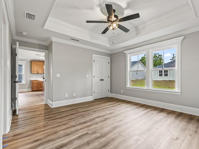 unfurnished bedroom featuring a raised ceiling, crown molding, and hardwood / wood-style floors