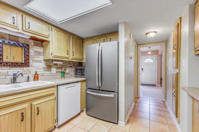 kitchen featuring stainless steel appliances, sink, light tile patterned floors, and decorative backsplash