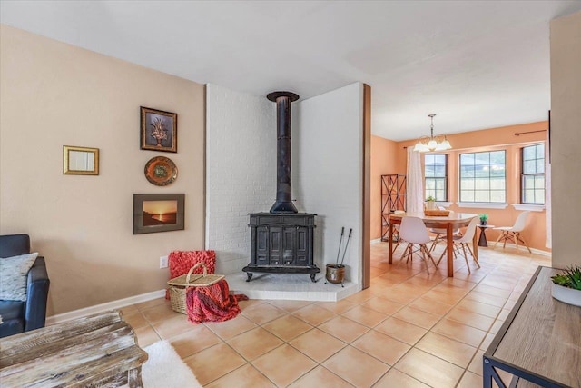 living room featuring a notable chandelier, light tile patterned floors, and a wood stove