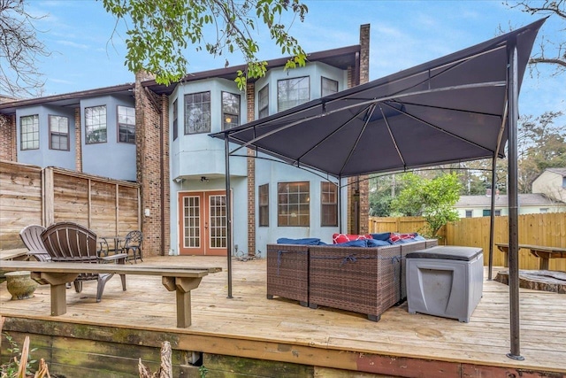 wooden terrace with a gazebo, outdoor lounge area, and french doors