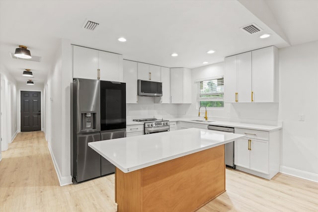 2224 Keith St, Tallahassee, FL 32310 - kitchen with stainless steel appliances, light wood-style floors, white cabinets, a kitchen island, and recessed lighting