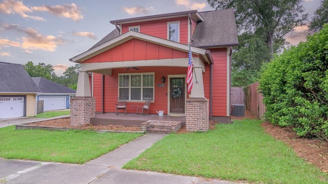 view of front of home featuring a garage, a porch, central AC, and a yard