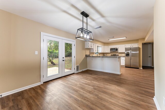2053 Ted Hines Dr, Tallahassee, FL 32308 - kitchen featuring appliances with stainless steel finishes, a peninsula, white cabinetry, wood finished floors, and french doors