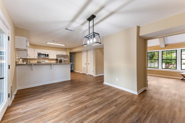 2053 Ted Hines Dr, Tallahassee, FL 32308 - kitchen featuring appliances with stainless steel finishes, wood finished floors, white cabinetry, a peninsula, and a breakfast bar area