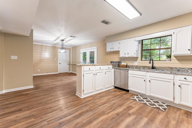 2053 Ted Hines Dr, Tallahassee, FL 32308 - kitchen featuring stainless steel dishwasher, a peninsula, plenty of natural light, white cabinetry, and wood walls