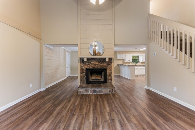 2053 Ted Hines Dr, Tallahassee, FL 32308 - unfurnished living room featuring a towering ceiling, dark wood-style flooring, a stone fireplace, and stairway