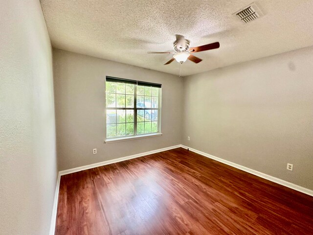 empty room with dark hardwood / wood-style flooring, a textured ceiling, and ceiling fan