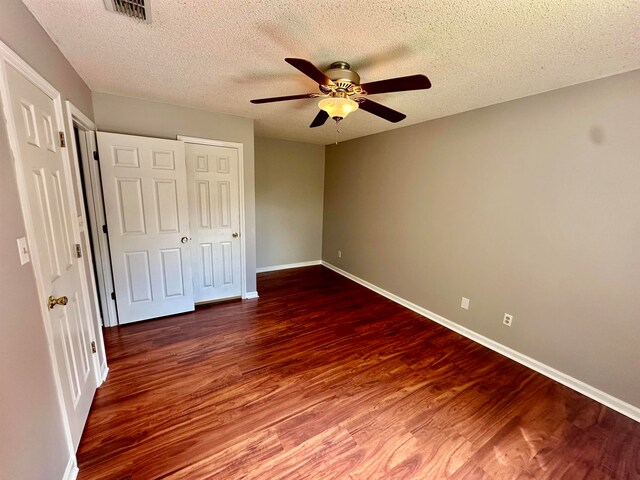 unfurnished bedroom with a textured ceiling, dark hardwood / wood-style flooring, ceiling fan, and a closet