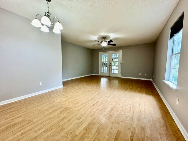 unfurnished room featuring light wood-type flooring, a textured ceiling, french doors, and ceiling fan with notable chandelier