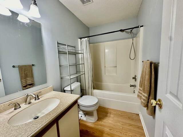 full bathroom with wood-type flooring, shower / bath combo with shower curtain, toilet, a textured ceiling, and vanity