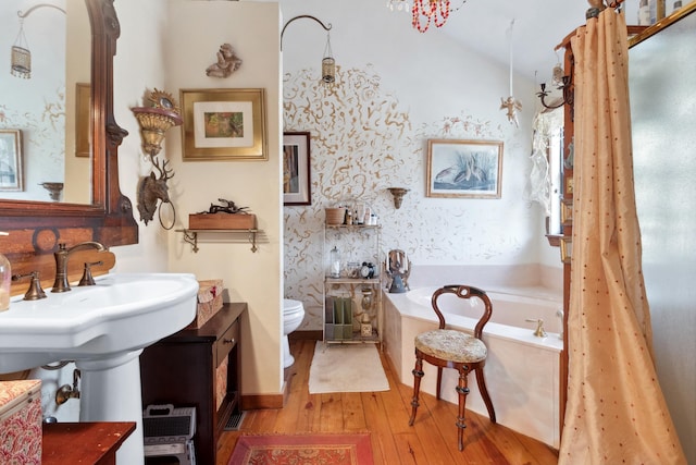 bathroom with hardwood / wood-style flooring, toilet, and a tub