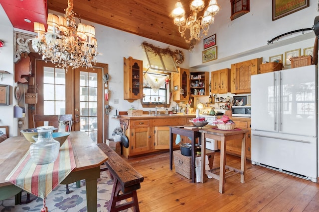 kitchen with high vaulted ceiling, decorative light fixtures, white appliances, and an inviting chandelier