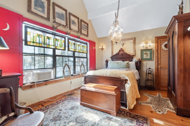 bedroom featuring lofted ceiling with beams, light hardwood / wood-style flooring, and a notable chandelier