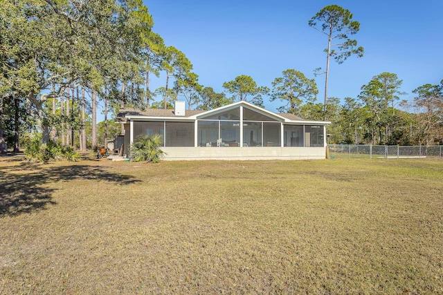 rear view of property featuring a sunroom and a lawn