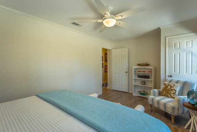 bedroom with dark wood-type flooring, ornamental molding, and ceiling fan