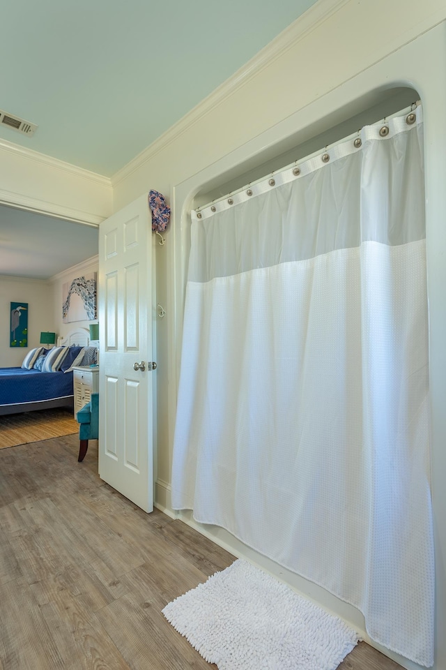 bathroom with crown molding and hardwood / wood-style flooring