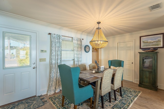 dining area with wood-type flooring, a chandelier, and crown molding