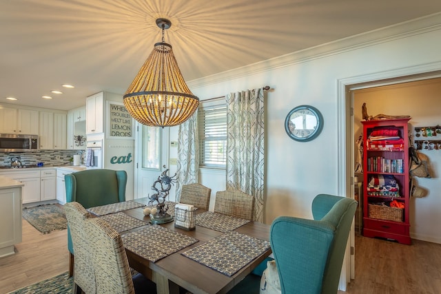 dining room with ornamental molding, a chandelier, and light wood-type flooring