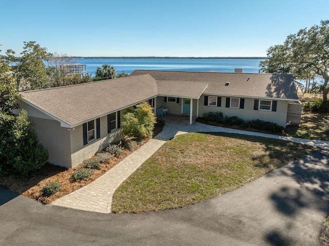 ranch-style home featuring a water view and a front lawn