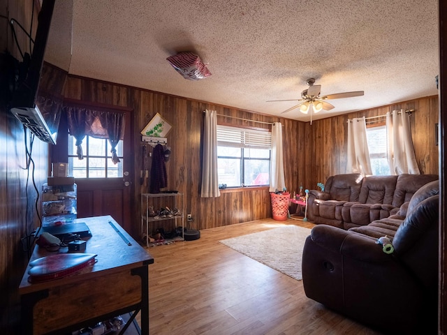 living area with wood walls, a textured ceiling, and wood finished floors