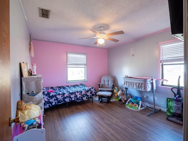 bedroom featuring crown molding, visible vents, ceiling fan, a textured ceiling, and wood finished floors