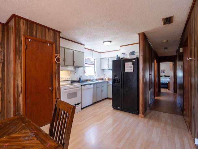 kitchen with white appliances, visible vents, light countertops, ornamental molding, and light wood finished floors