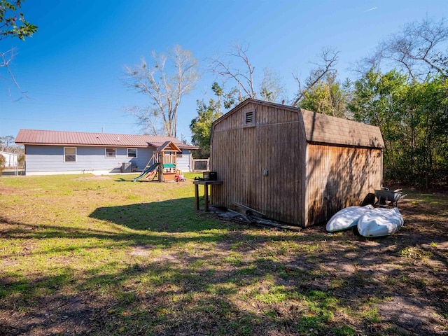 view of yard with a playground, an outdoor structure, and a storage unit