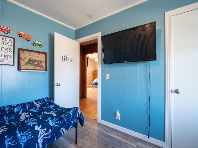 bedroom featuring ornamental molding and wood finished floors