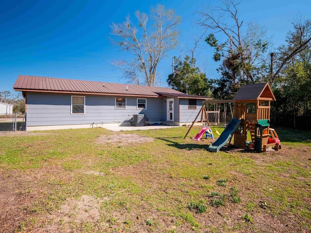 rear view of property featuring a playground, metal roof, and a lawn