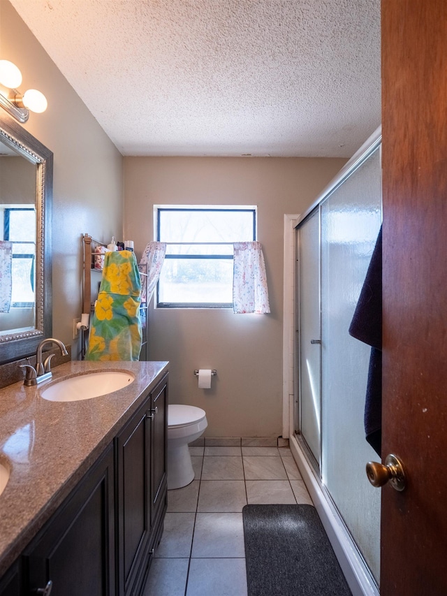 full bathroom with a textured ceiling, tile patterned flooring, vanity, and a shower stall