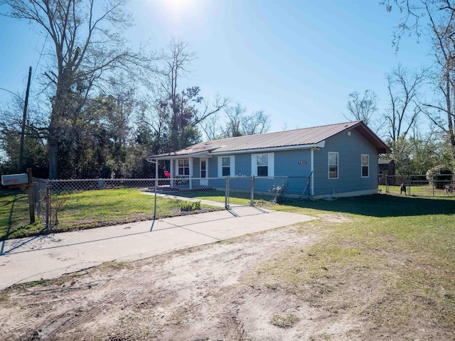 view of front of home with metal roof, a fenced front yard, dirt driveway, and a front lawn