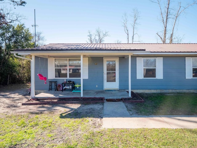 view of front of home with a front yard, covered porch, and metal roof